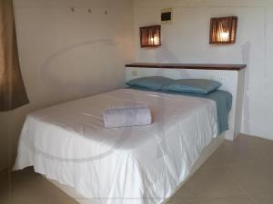 a bed in a room with a white sheets and blue pillows at Seaside Nord in Máncora