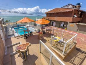 a balcony with a pool and tables and umbrellas at RECANTO DO FLOR in Japaratinga