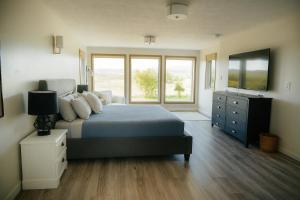 a bedroom with a bed with a television and a dresser at Hot-tub, Games Room, Walk-in Sauna, 7 BM, 15 mins to Waterton in Mountain View
