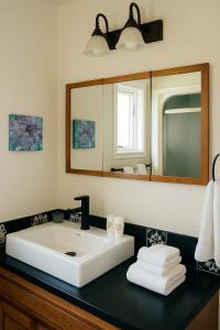 a bathroom with a white sink and a mirror at Hot-tub, Games Room, Walk-in Sauna, 7 BM, 15 mins to Waterton in Mountain View +58 photos