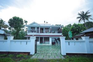 a house with a white fence in front of it at Wayanadan Huts Homestay in Sultan Bathery