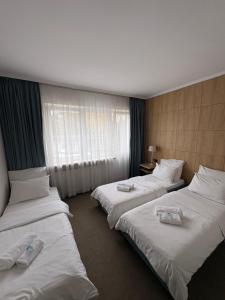 three beds in a hotel room with towels on them at Villa Gold Poznań in Poznań