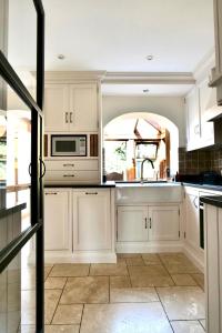 a kitchen with white cabinets and a sink and a microwave at Characterful holiday home in Oxfordshire Cotswolds 