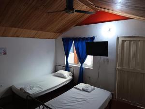 two beds in a room with a tv and a window at Hotel Efata in Apartadó