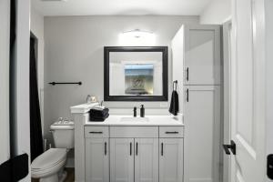 a white bathroom with a sink and a toilet at Towson Elite Apartment in Towson
