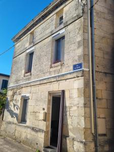 a stone building with a door and a sign on it at bien-être in Bourg-sur-Gironde