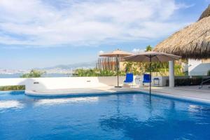 a swimming pool with an umbrella and two chairs at Villa MAJUM Acapulco in Acapulco
