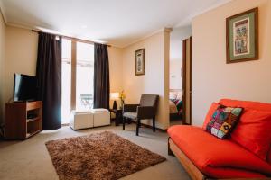 a living room with a red couch and a television at Hotel Chalet Valluga in Farellones