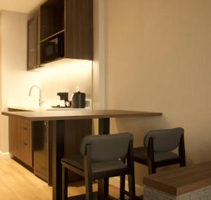 a kitchen with a counter with two chairs and a sink at Armon Plaza Montreal Airport in Montréal