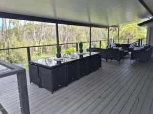 une terrasse avec des tables et des canapés sur un porche dans l'établissement Skyes Beach House-Views, Spas, Sauna, Arcade Games, à Surf Beach