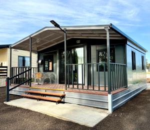 a tiny house with a porch and a deck at Corryong Caravan Park in Corryong
