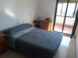 a bedroom with a bed and a desk and window at Room next to Gibraltar in La Línea de la Concepción