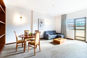 a living room with a dining room table and a couch at Hotel La Fontaine in Esmoriz