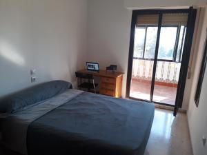 a bedroom with a bed and a desk and a window at Room next to Gibraltar in La Línea de la Concepción