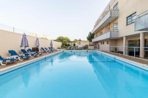 a large swimming pool with chairs and umbrellas at Hotel La Fontaine in Esmoriz