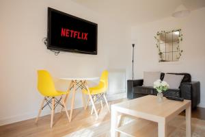 ein Wohnzimmer mit gelben Stühlen und einem Fernseher an der Wand in der Unterkunft Modern 2-Bed Apartment in Central Portsmouth in Portsmouth