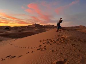 a woman standing on a sand dune in the desert at sahara bliss camp in Merzouga