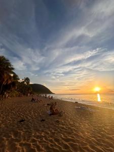 哥西尔Villa Au Coeur des Iles - Marina Gosier的日落时分海滩上的一群人