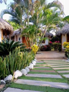 a walkway in front of a house with palm trees at Cabañas Riviera Pacific in Pedernales +47 photos