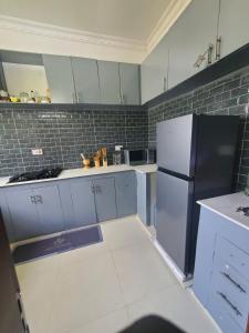 a kitchen with white cabinets and a refrigerator at Zurihomes in Dar es Salaam