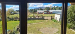 a window view of a farm with a house at Al pie del león in Ñirihuau +2 photos