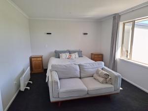 a bedroom with a bed and a couch and a window at The Mews - Country Stay in Rolleston