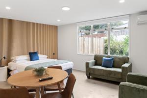 a bedroom with a bed and a table and a chair at Pacific Motor Inn in Mount Maunganui