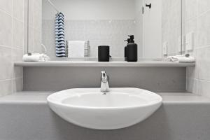 a white sink in a bathroom with a mirror at Pacific Motor Inn in Mount Maunganui
