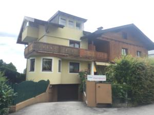 Una gran casa amarilla con un balcón en la parte superior. en Haus Kernstock en Salzburgo