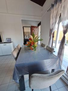a blue table with chairs and a vase of flowers on it at Kaz'Agatha in Sainte-Anne