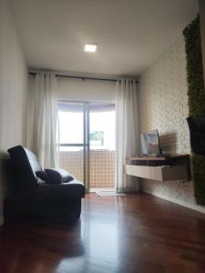 a living room with a couch and a large window at Apartment in the heart of Joinville in Joinville