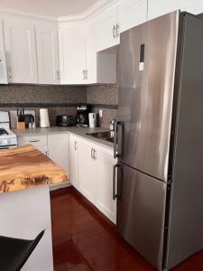a kitchen with a stainless steel refrigerator and white cabinets at Furnished Rooms in North Vancouver