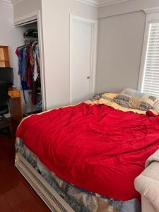 a bedroom with a bed with a red blanket at Furnished Rooms in North Vancouver