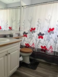 a bathroom with a toilet and a shower curtain with red flowers at Furnished Rooms in North Vancouver