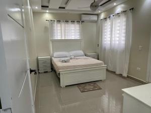 a white bedroom with a bed and a window at Cómodo apto punta Popi a un minuto de la playa in Las Terrenas