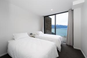 two white beds in a room with a large window at The Alpine Lakeview Luxe Retreat in Queenstown