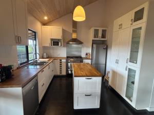a kitchen with white cabinets and a wooden counter top at Valley Cottage, Treeton winery, Margaret River in Cowaramup