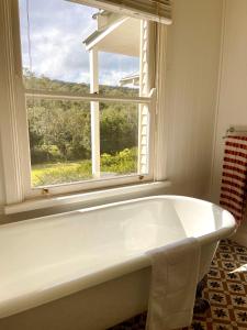 Una bañera blanca en un baño con ventana. en Nightcap Ridge - Byron Bay Hinterland, en Dorroughby