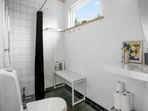 a white bathroom with a toilet and a window at 5 star holiday home in Allingåbro in Rygård Strand +7 photos