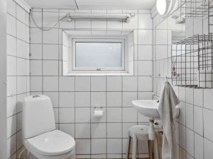 a white bathroom with a toilet and a sink at 5 star holiday home in Haderslev in Flovt +13 photos