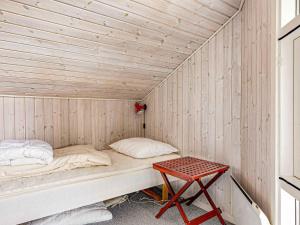 a small bed in a wooden room with a table at 5 star holiday home in Store Fuglede in Ornum