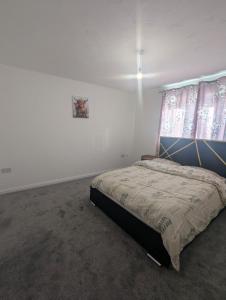 a bedroom with a bed in a white room at 3SIEE Homes in Luton