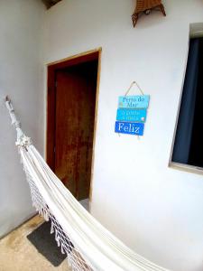 een hangmat in een kamer met een bord aan de muur bij Vila das Conchas - Estalagem in Japaratinga
