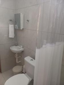 een witte badkamer met een toilet en een wastafel bij Vila das Conchas - Estalagem in Japaratinga