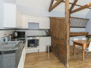 a kitchen with white cabinets and a wooden table at Ingleby Barn - 27946 in Battersby