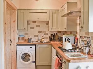 a kitchen with white cabinets and a washing machine at The Old Chapel in Burshill