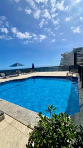 une grande piscine bleue avec l'océan en arrière-plan dans l'établissement Flat Pituba Sol - conforto e ótima localização, à Salvador