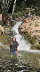 una mujer parada en el agua frente a una cascada en Apart melgar familiar, en Girardot
