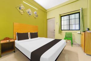 a bedroom with a large bed and a green wall at Hotel O Magical Crown Inn in Tudiyalūr