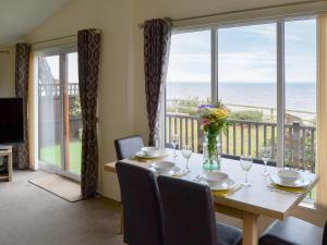a dining room with a table with a view of the ocean at Ocean Glade - Uk32963 in Corton